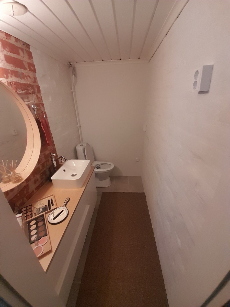 Kapea WC-tila: tiiliyksityiskohta, pyöreä peili ja allastaso