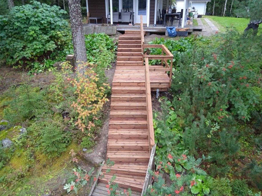 Puuterassi ja portaat rinteessä, kaiteet ja huollettu kulkuyhteys pihalta