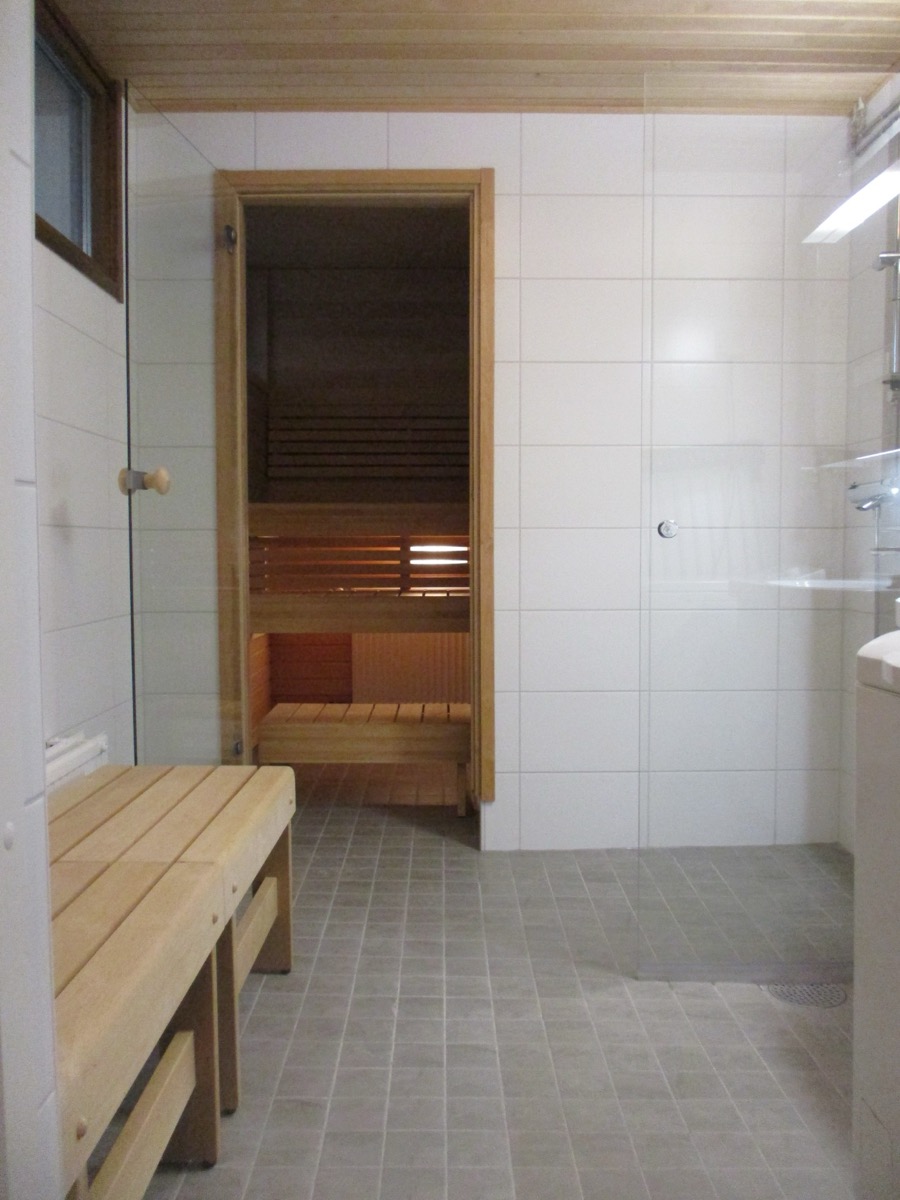 Pesuhuone ja sauna: lasiovi saunaan, puulauteet ja laatoitettu lattia