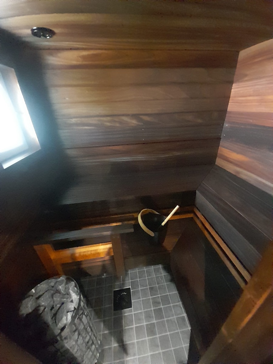 Sauna: puulauteet, kiuas ja laatoitettu lattia lattiakaivoineen